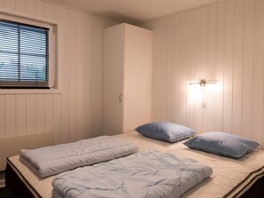 A bedroom with a bed, two pillows, a wardrobe, a window with blinds, and a wall-mounted light fixture. - 8 Person Holiday Home on a Holiday Park in Blåvand (Blavand)