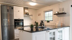 Une cuisine moderne avec des meubles blancs, des appareils en acier inoxydable et un plan de travail noir.