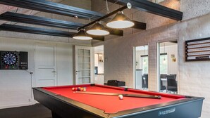 Une table de billard avec des billes, un jeu de fléchettes et un porte-queue de billard.