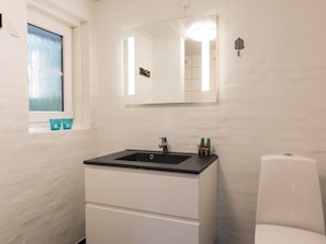 A bathroom with a white sink, a mirror, and a toilet. - 8 Person Holiday Home on a Holiday Park in Blåvand (Blavand)
