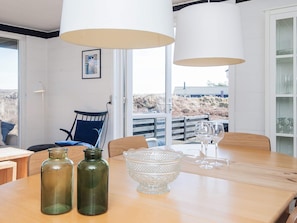 A dining area with a wooden table, two chairs, a glass bowl, and two wine glasses. - 4 Person Holiday Home in Fano (Fano)
