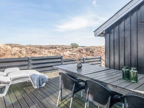 En träaltan med ett bord och stolar, en bänk och utsikt över landskapet.
