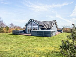 A modern house with a large deck, a covered patio, and a well-maintained lawn. - Holiday Home in Tarm (Tarm)