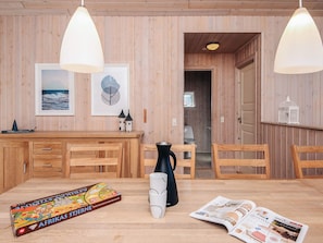 Un interior de madera con una mesa de comedor, sillas, una cafetera y una revista.