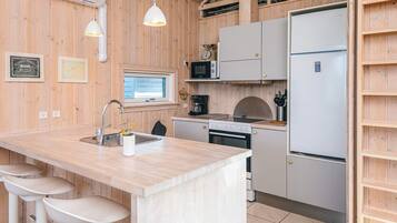 A compact kitchen with a central island, a microwave, a stove, and a refrigerator.