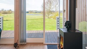 A modern room with a large sliding glass door leading to an outdoor deck, a fireplace, and a small dog figurine. - Holiday Home in Tarm (Tarm)