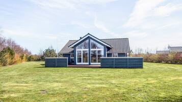 A modern house with a large glass front, a sloped roof, and a well-maintained lawn.