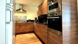 Uma cozinha moderna com armários de madeira, eletrodomésticos de aço inoxidável e forno embutido.