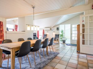 Een eetgedeelte met een houten tafel en stoelen, een plafondventilator en uitzicht op de omgeving.