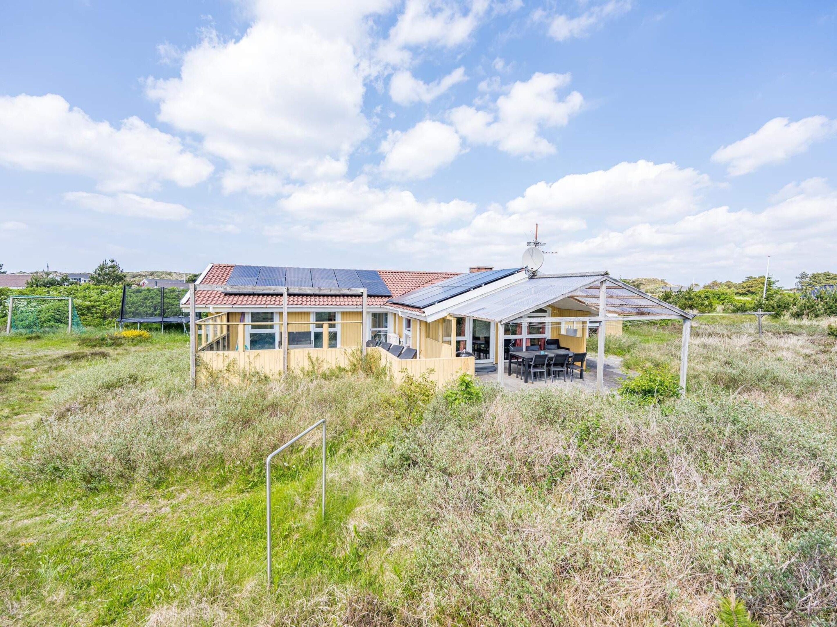 A house with a solar panel roof, a covered patio, and a satellite dish.