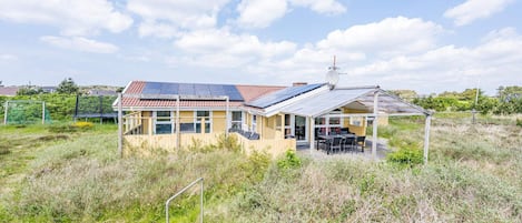 A house with a solar panel roof, a covered patio, and a satellite dish.