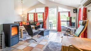 A cozy room with a fireplace, seating, and a TV. - 4 Star Holiday Home in Henne (Henne)