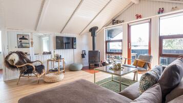 A cozy living room with a sofa, a coffee table, and a television mounted on the wall.