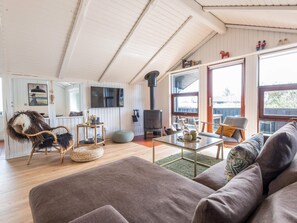 A cozy living room with a sofa, a coffee table, and a television mounted on the wall. - 4 Star Holiday Home in Fano (Fano)