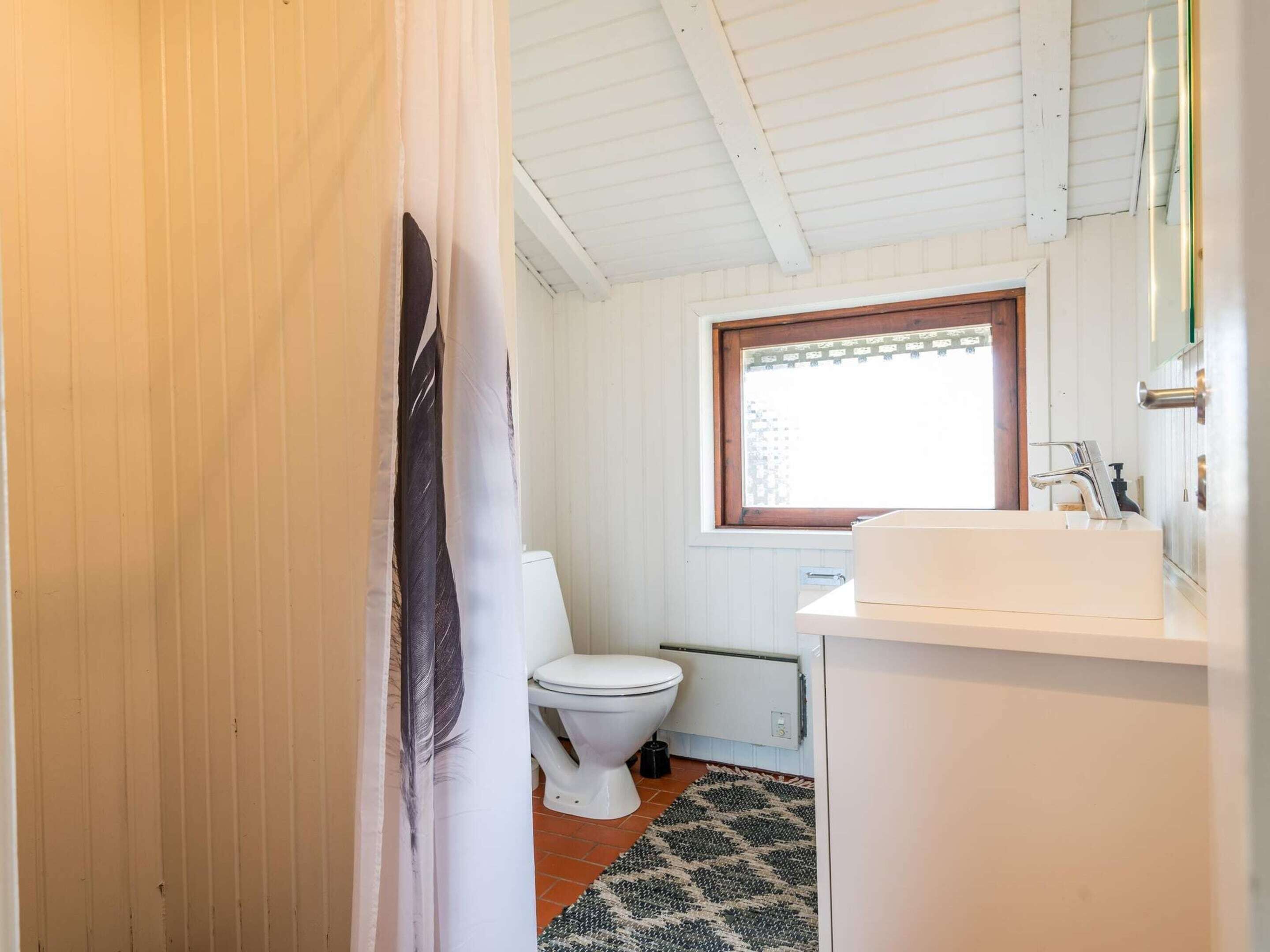 A bathroom with a toilet, sink, and window.