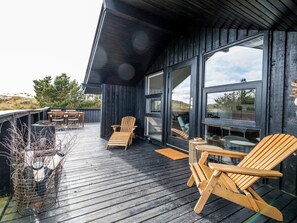 A deck with wooden chairs and tables, large windows, and a view of the landscape. - 4 Star Holiday Home in Fano (Fano)