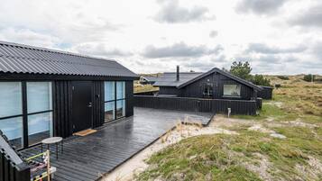 A modern wooden house with large windows and a deck.