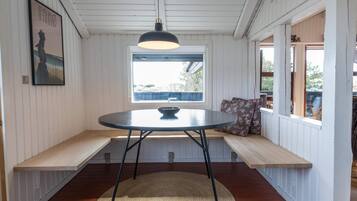 A room with a round table, bench seating, a window, and a hanging light fixture.