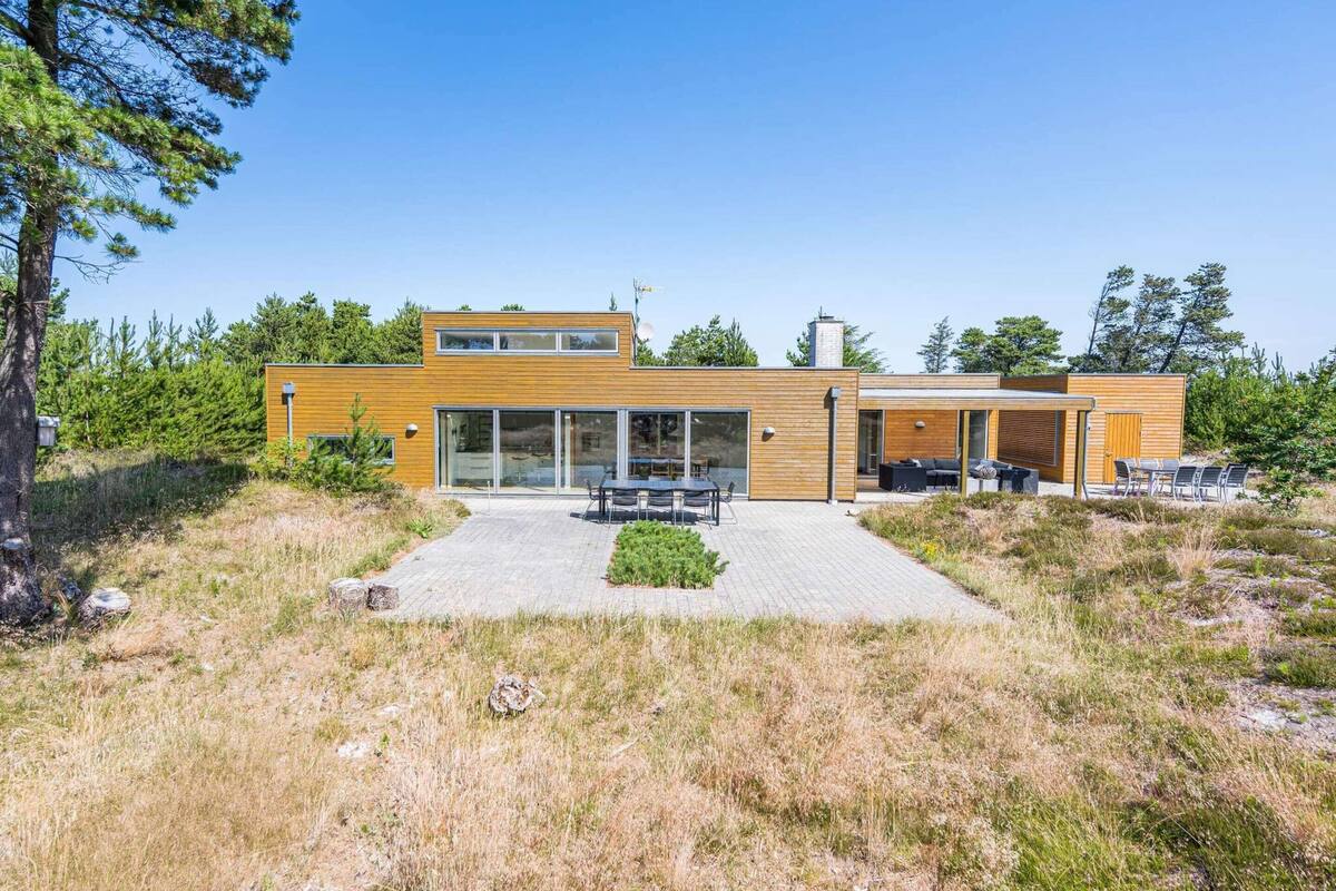 A modern two-story house with a patio area, large windows, and a chimney.