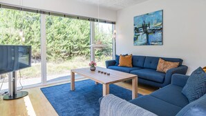 A modern living room with a blue sofa, a coffee table, and a TV. - 6 Person Holiday Home in Henne (Henne)