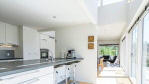 A modern kitchen with white cabinets, a stainless steel countertop, and a coffee machine. - 6 Person Holiday Home in Henne (Henne)