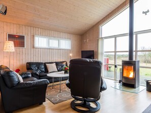 A cozy room with a leather sofa, a round table, and a modern fireplace.