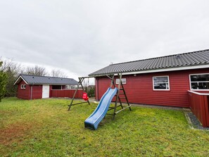 A red building with a blue slide in a grassy yard.