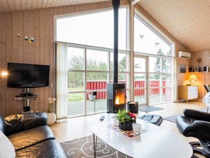 A modern living room with a fireplace, a flat-screen TV, leather sofas, and a dining area. - 4 Star Holiday Home in Tarm (Tarm)