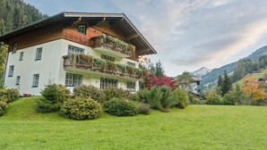 A multi-story building with balconies, surrounded by lush greenery and mountains in the background. - Apartment Grossarl Near Ski Slopes (Grossarl)