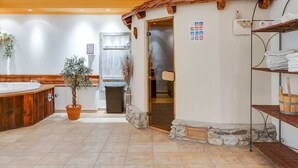 A bathroom with a wooden bathtub, a potted plant, a stone wall, and a towel rack. - Apartment Grossarl Near Ski Slopes (Grossarl)