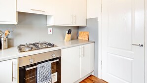 Eine Küche mit weißen Schränken, einem Gasherd, einem Backofen und einer Holzarbeitsplatte.