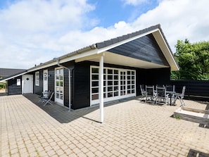 A building with a covered patio area, large windows, and outdoor seating.