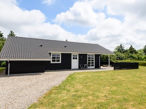 A black building with a tiled roof, a gravel driveway, and a grassy lawn. - 4 Star Holiday Home in Tarm (Tarm)