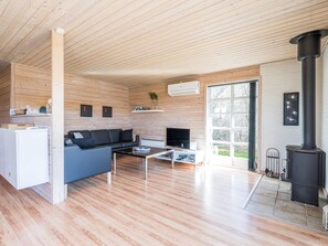 A modern interior with a wooden ceiling, a sofa, a coffee table, a TV, and a fireplace. - 4 Star Holiday Home in Tarm (Tarm)