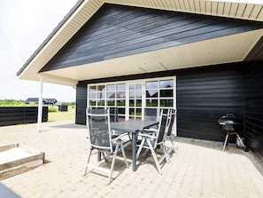 A covered outdoor patio with a table and chairs, a grill, and a view of the surrounding area. - 4 Star Holiday Home in Tarm (Tarm)