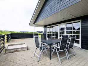 An outdoor patio with a table and chairs, a covered seating area, and a view of the surrounding landscape. - 4 Star Holiday Home in Tarm (Tarm)