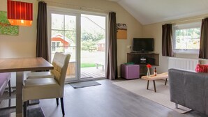 A spacious living area with a dining table, chairs, a sofa, a television, and a view of the outdoors. - Cozy Cottage With Dishwasher, Near Utrecht (Maarn)