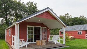 A red cabin with a covered porch, two white Adirondack chairs, and a wooden table. - Cozy Cottage With Dishwasher, Near Utrecht (Maarn)