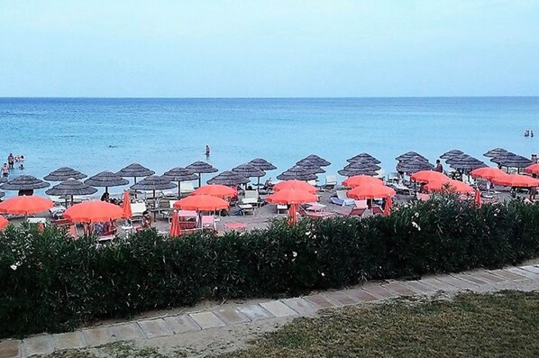 A beach with rows of umbrellas and lounge chairs.