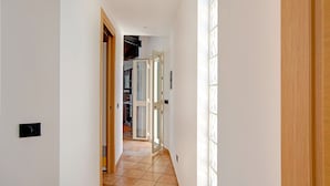 A hallway with a tiled floor, wooden doors, and a view into a kitchen area. - Beachside Getaway w/ Garden (Noto)