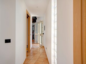A hallway with a tiled floor, wooden doors, and a view into a kitchen area.