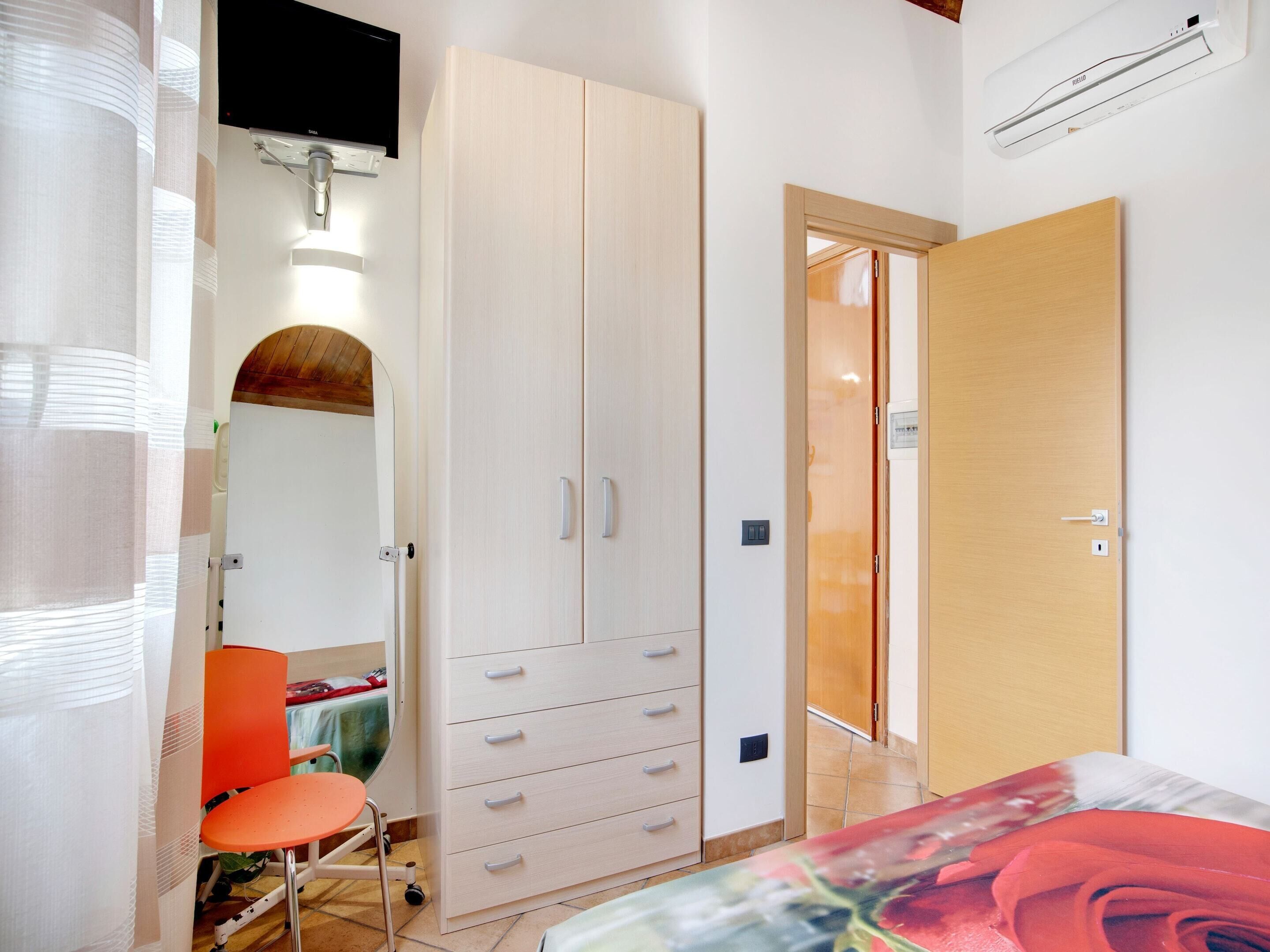Un dormitorio con cama, armario, silla y televisor.