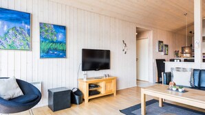 A modern living room with a flat-screen TV, wooden furniture, and two paintings on the wall. - 5 Star Holiday Home in Tarm (Tarm)