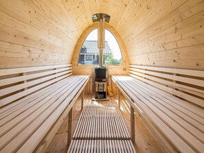 A wooden sauna with benches and a sauna unit.