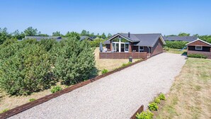 A row of cabins with a gravel driveway leading to the entrance, surrounded by dense greenery. - 5 Star Holiday Home in Tarm (Tarm)