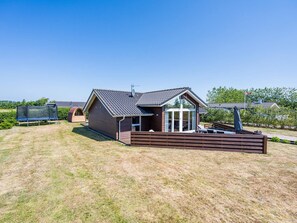 A single-story house with a covered patio, a fenced yard, and a trampoline.