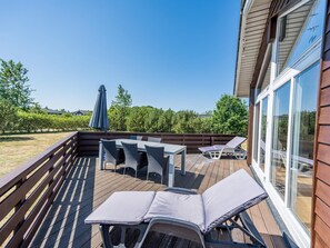 A deck with outdoor furniture, including a table and chairs, and a lounge chair.