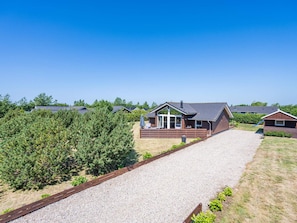 A residential area with multiple houses, a gravel driveway, and a clear sky.