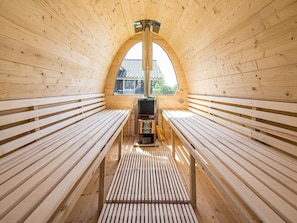 A sauna with wooden benches and a central heating unit.