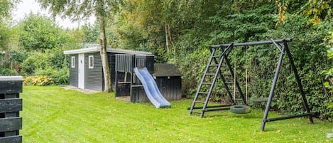 A backyard with a play area including a slide and a swing set.